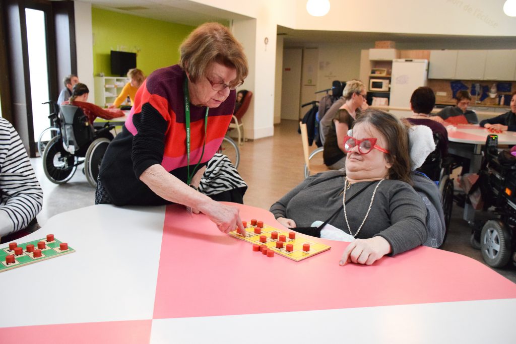 Une bénévole aidant une résidente de la Mosaïque lors du loto