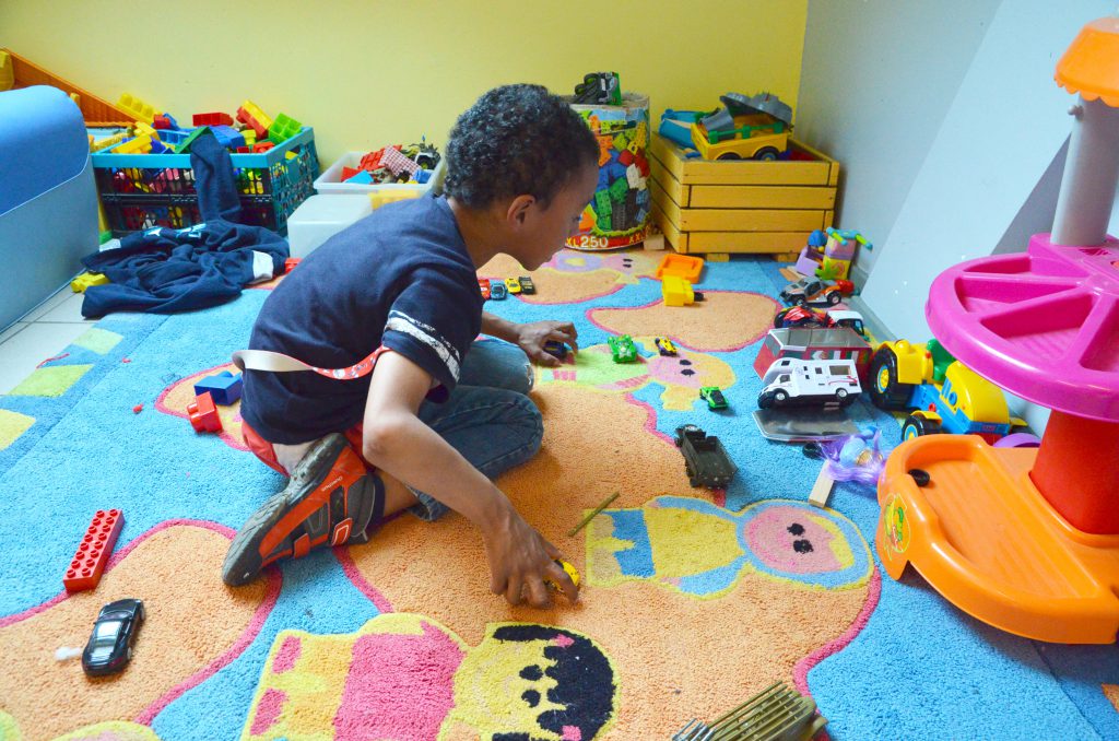 Petit garçon jouant aux petites voitures sur un tapis coloré